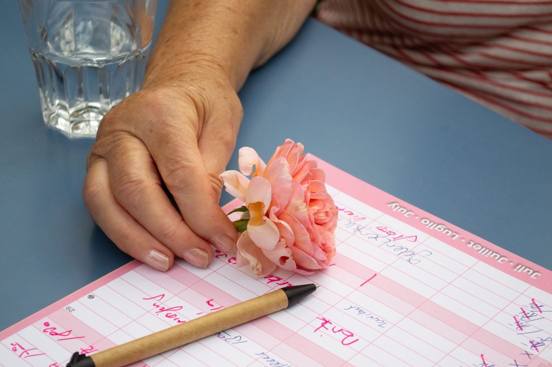 Eine Hand legt eine Rose auf einen handgeschriebenen Wochenplaner